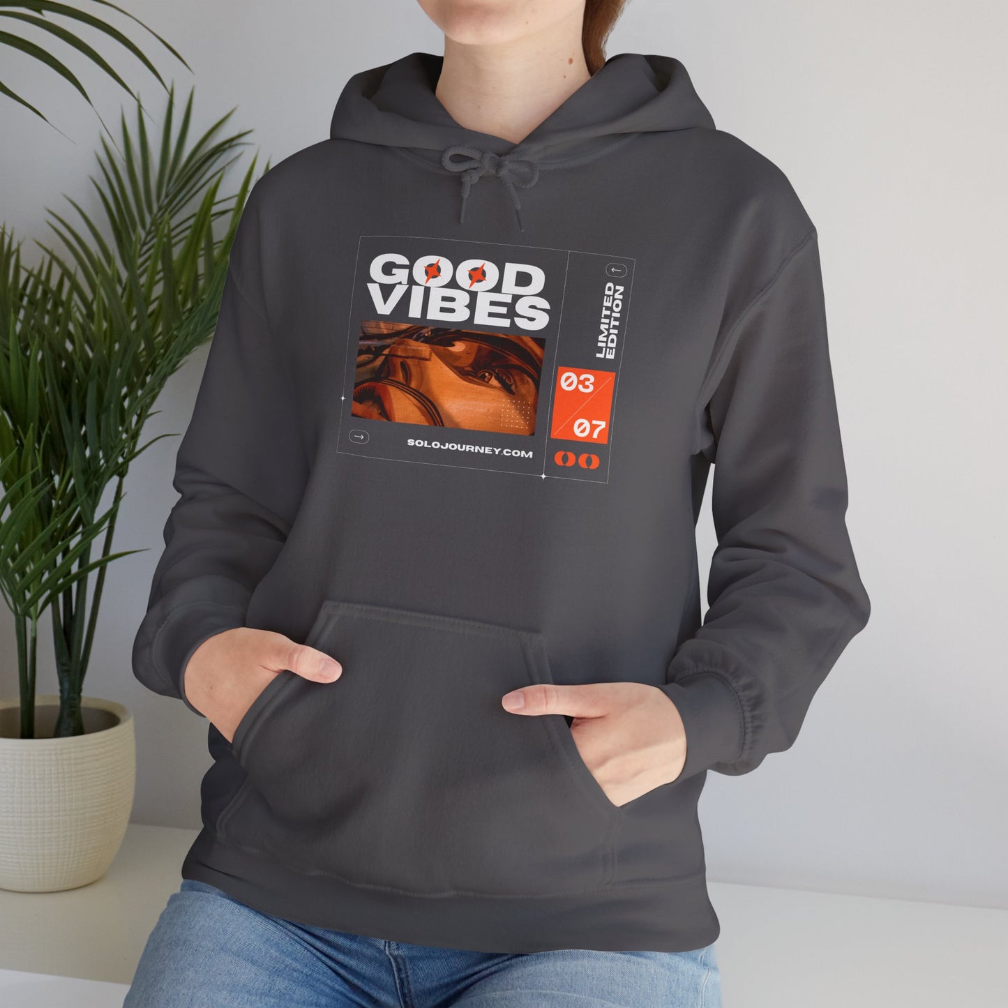Good Vibes Unisex Heavy Blend Hoodie in a stylish casual setting, showcasing its eco-friendly organic cotton fabric and trendy design.